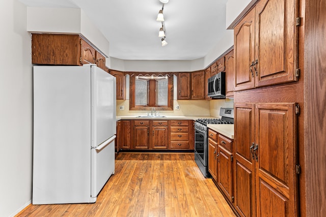 kitchen with sink, wood-type flooring, stainless steel appliances, and rail lighting