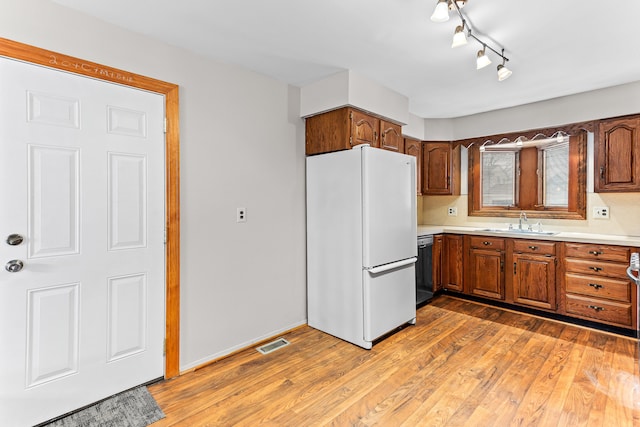 kitchen featuring white fridge, sink, stainless steel dishwasher, and light hardwood / wood-style flooring