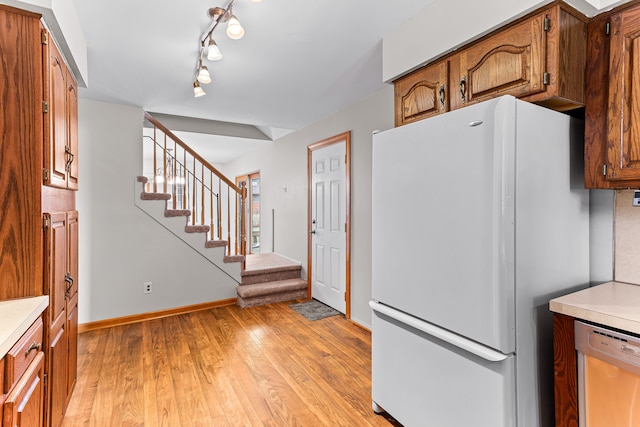 kitchen with track lighting, light wood-type flooring, stainless steel dishwasher, and white refrigerator