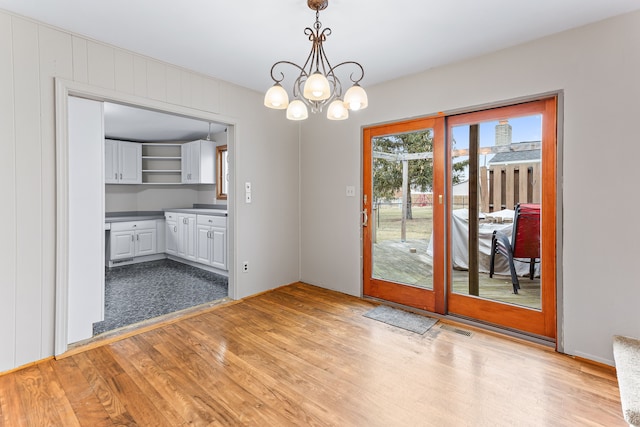 interior space featuring decorative light fixtures, a chandelier, light hardwood / wood-style flooring, and white cabinets