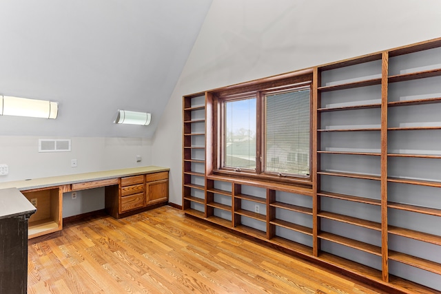 home office featuring built in desk, vaulted ceiling, and light hardwood / wood-style flooring