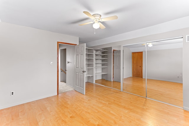 unfurnished bedroom featuring ceiling fan, hardwood / wood-style floors, and two closets