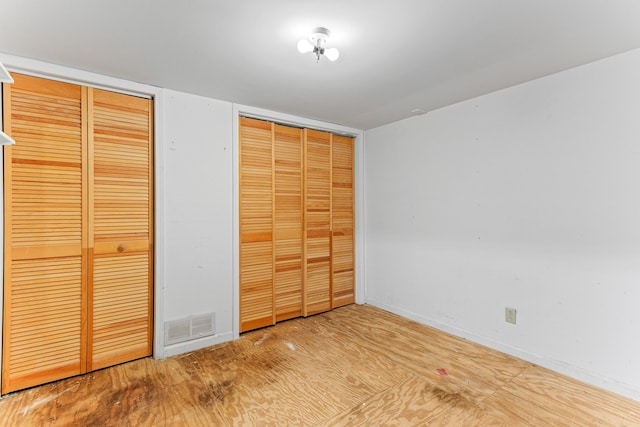 unfurnished bedroom with multiple closets and hardwood / wood-style floors