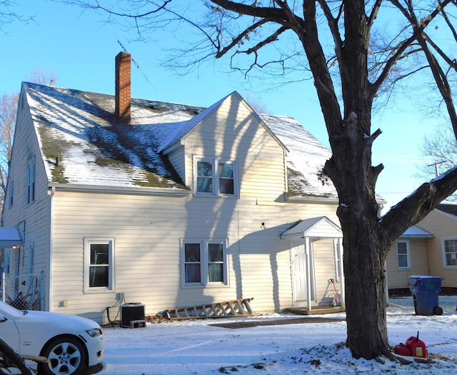 snow covered house featuring central AC unit