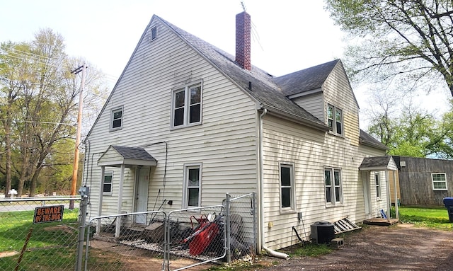 rear view of house featuring a chimney, central AC unit, fence private yard, a gate, and a shingled roof