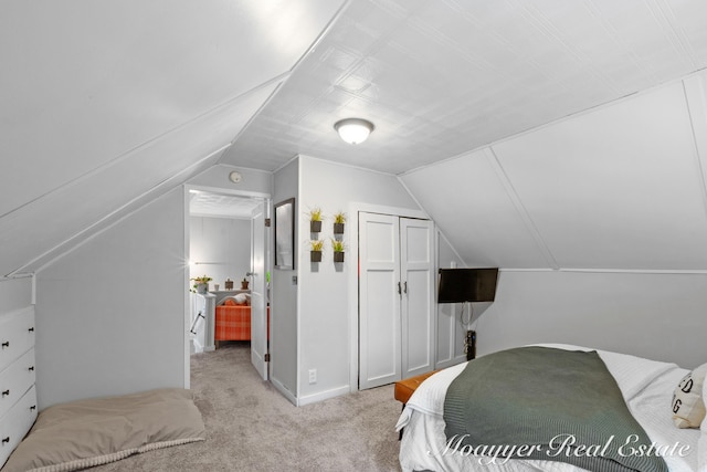 bedroom with vaulted ceiling, light colored carpet, and a closet