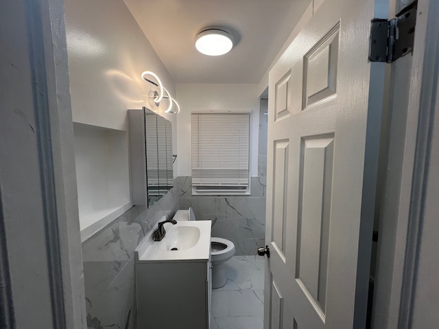 bathroom with vanity, toilet, and tile walls