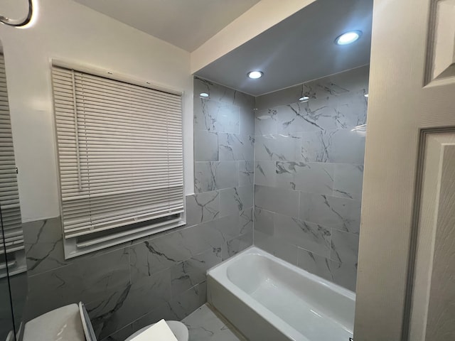 bathroom featuring tiled shower / bath combo, tile walls, and toilet