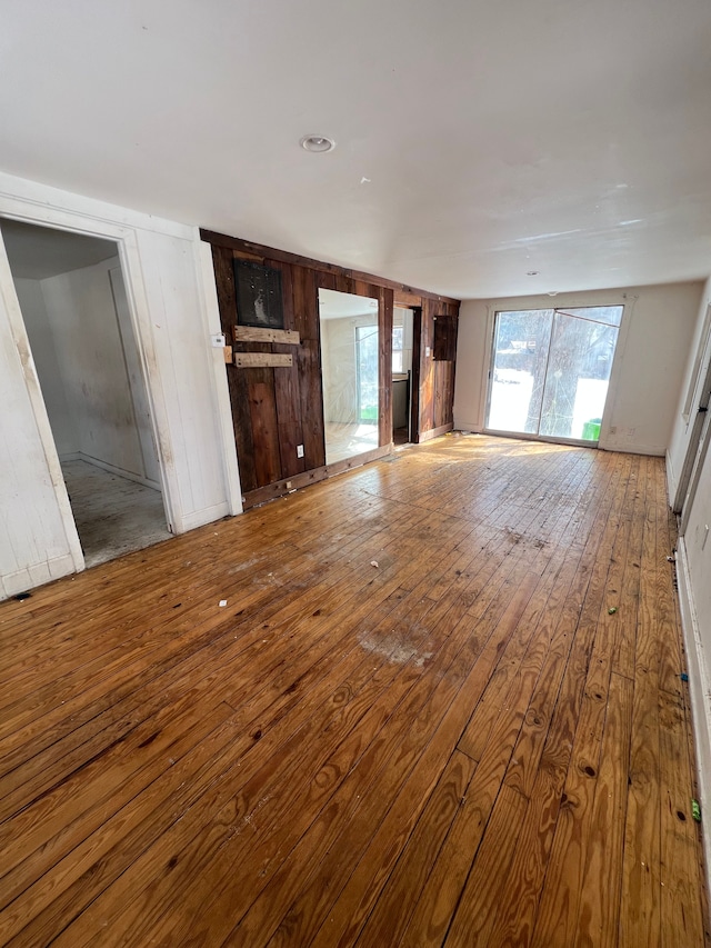 unfurnished living room with hardwood / wood-style flooring and wooden walls