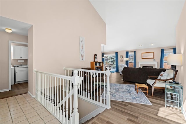 corridor featuring high vaulted ceiling and light hardwood / wood-style flooring