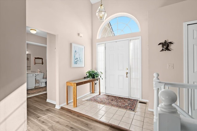 foyer entrance featuring light hardwood / wood-style flooring, a high ceiling, and an inviting chandelier