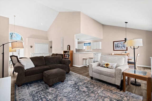 living room with a healthy amount of sunlight, high vaulted ceiling, and dark wood-type flooring