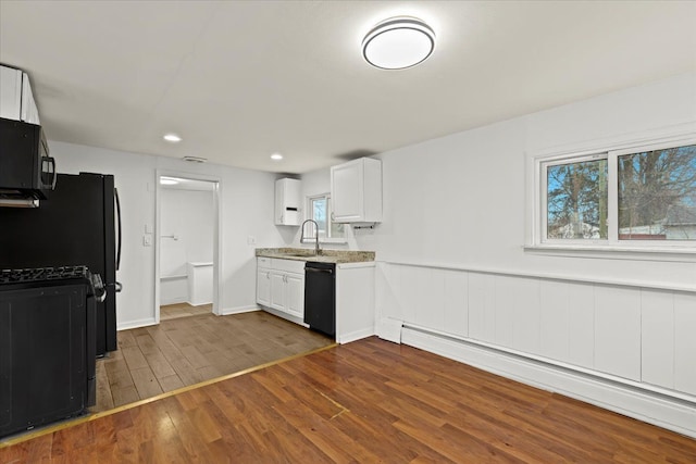 kitchen featuring white cabinets, a baseboard radiator, dark wood-type flooring, black appliances, and a sink