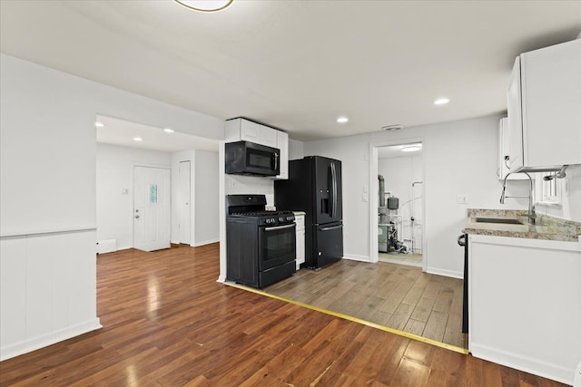 kitchen with recessed lighting, dark wood-type flooring, a sink, white cabinets, and black appliances