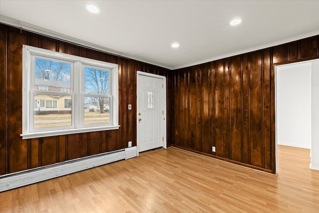 empty room featuring wooden walls, a baseboard radiator, light wood-style flooring, and recessed lighting