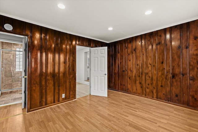 unfurnished room featuring light wood-style floors, wooden walls, and recessed lighting