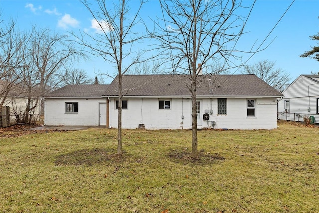 rear view of house with a shingled roof, a lawn, and fence