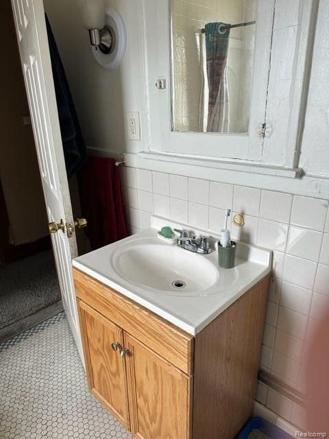 bathroom featuring vanity and tile walls