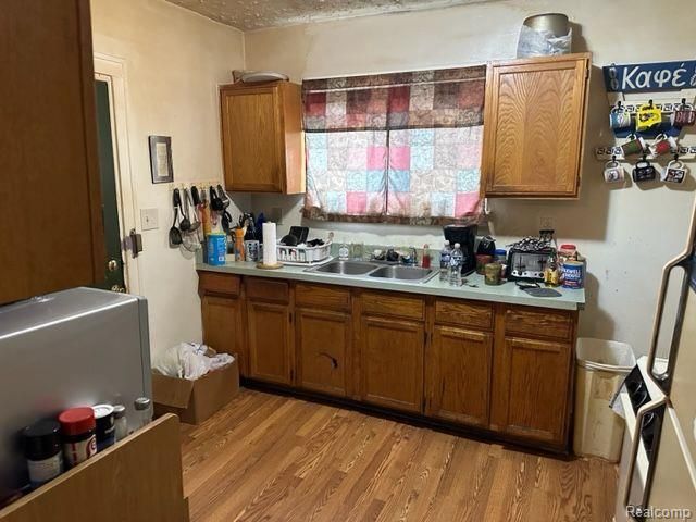 kitchen with sink, a textured ceiling, and light wood-type flooring