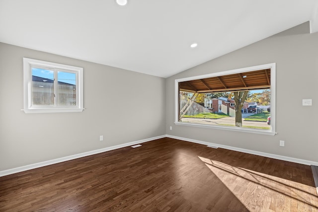 unfurnished room featuring lofted ceiling, a healthy amount of sunlight, and dark hardwood / wood-style flooring