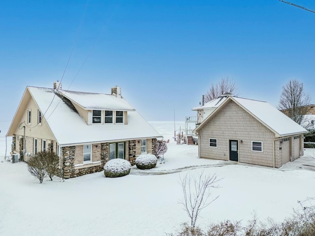 snow covered rear of property featuring a garage and central air condition unit