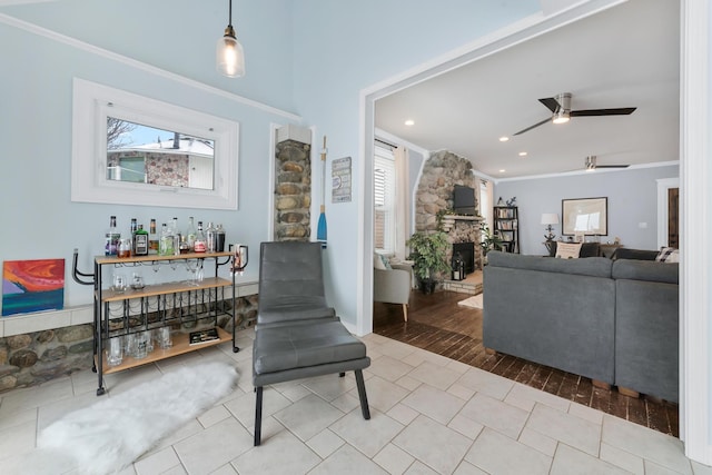 interior space featuring ceiling fan, ornamental molding, a stone fireplace, and a wealth of natural light