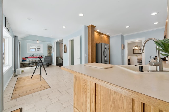 kitchen with stainless steel refrigerator with ice dispenser, crown molding, sink, and hanging light fixtures