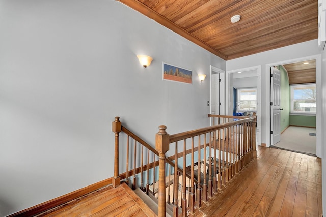 corridor with wood ceiling, ornamental molding, and hardwood / wood-style flooring