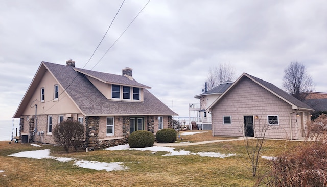 exterior space featuring stucco siding, a chimney, a front yard, and roof with shingles