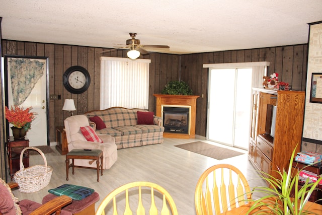 living room with light wood-type flooring, a textured ceiling, and wood walls