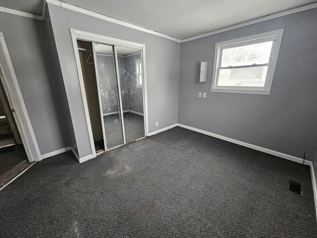 unfurnished bedroom with crown molding, dark carpet, and a closet