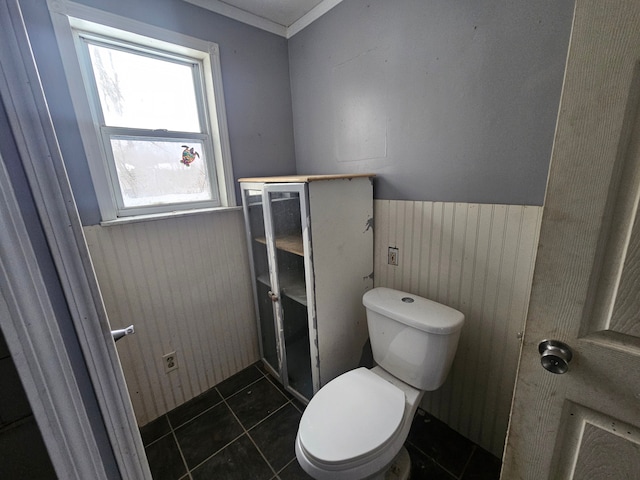 bathroom featuring tile patterned flooring, wooden walls, and toilet