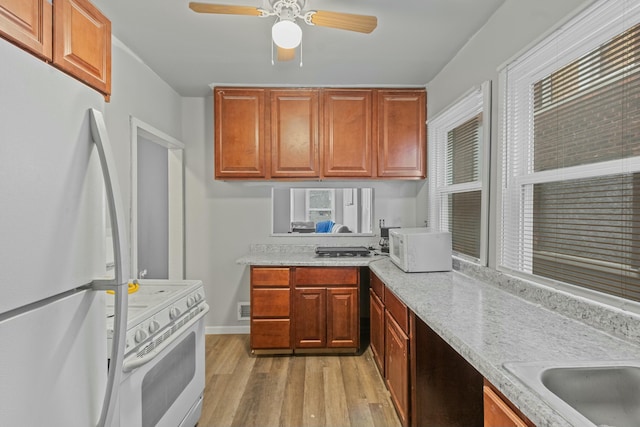 kitchen featuring light stone counters, white appliances, ceiling fan, and light hardwood / wood-style floors