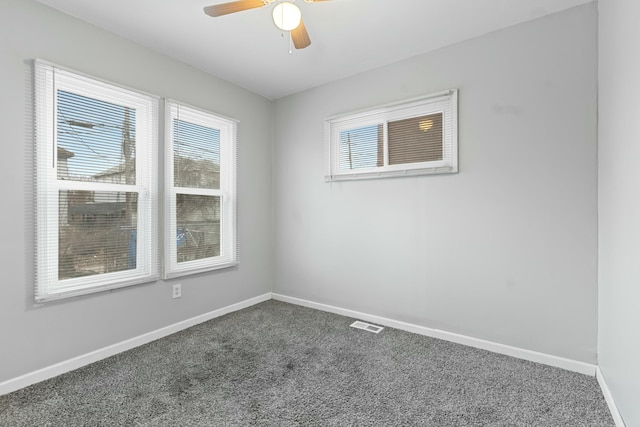 empty room with ceiling fan and dark colored carpet