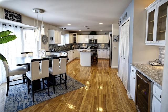 dining area featuring sink, beverage cooler, and light wood-type flooring