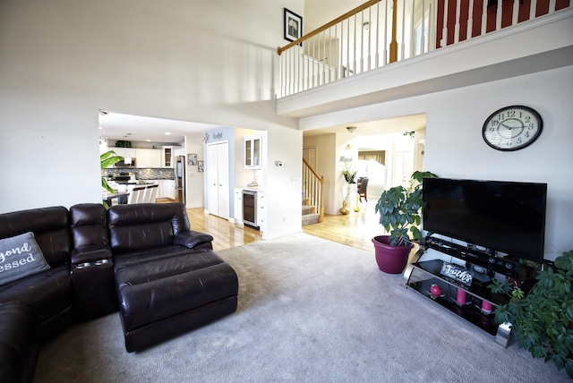 living room featuring wine cooler, light colored carpet, and a high ceiling