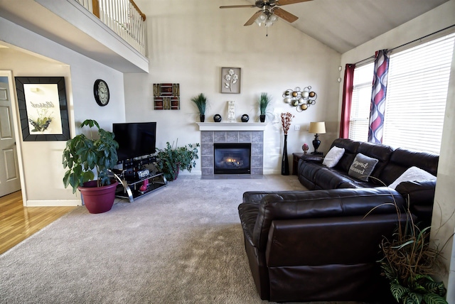 carpeted living room featuring a tile fireplace, ceiling fan, and high vaulted ceiling