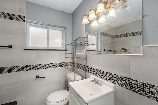 bathroom with vanity, toilet, and tile walls