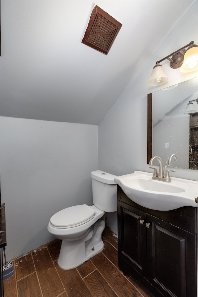 bathroom featuring vanity, vaulted ceiling, and toilet