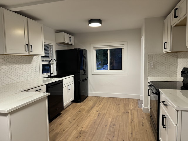 kitchen featuring sink, white cabinetry, light stone counters, light wood-type flooring, and black appliances