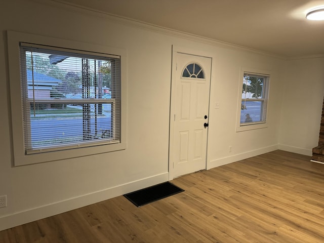 foyer featuring crown molding, a healthy amount of sunlight, and hardwood / wood-style flooring