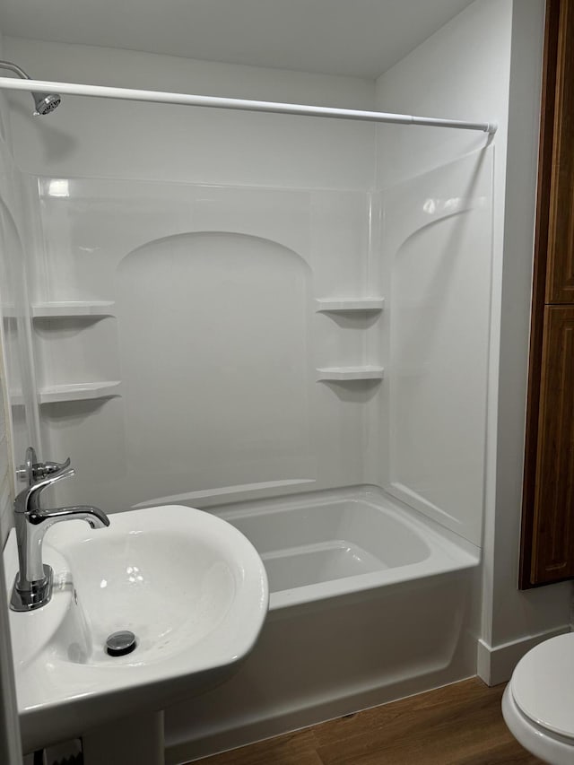 full bathroom featuring  shower combination, sink, hardwood / wood-style floors, and toilet