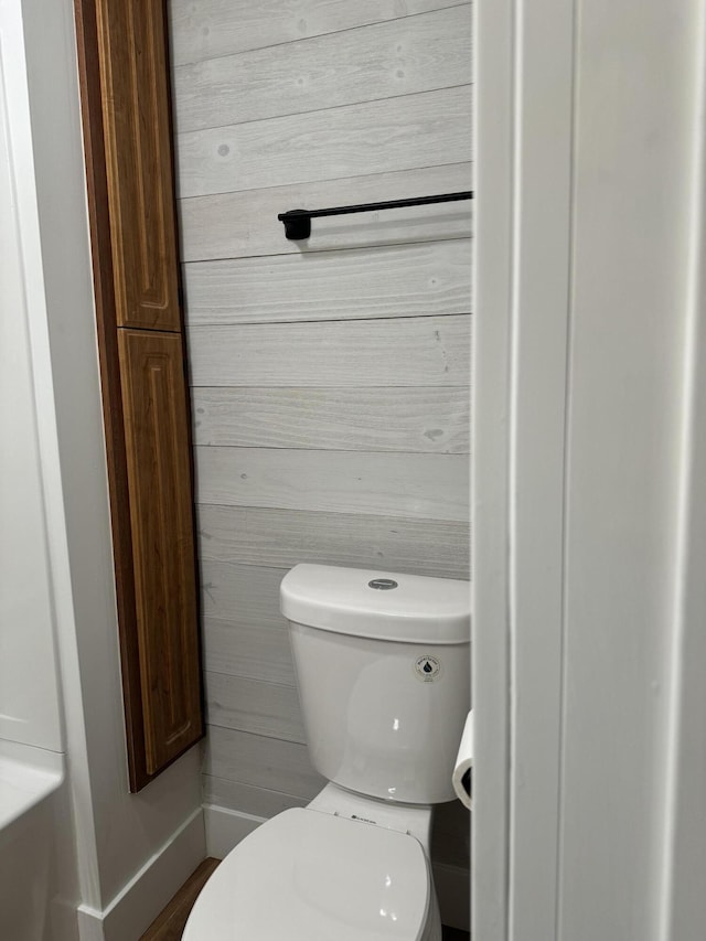 bathroom with wooden walls and toilet