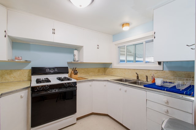 kitchen featuring gas range, white cabinetry, and sink