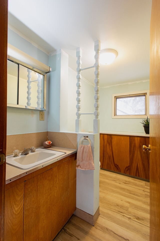 bathroom with wood-type flooring, vanity, and crown molding