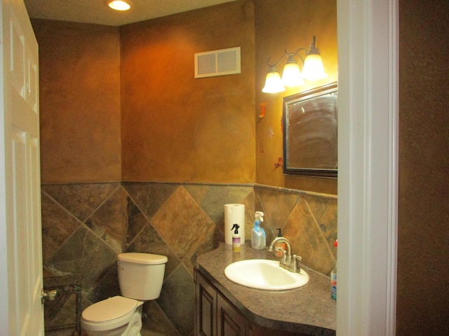 bathroom featuring vanity, tile walls, and toilet