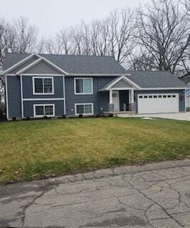 raised ranch featuring a garage and a front yard