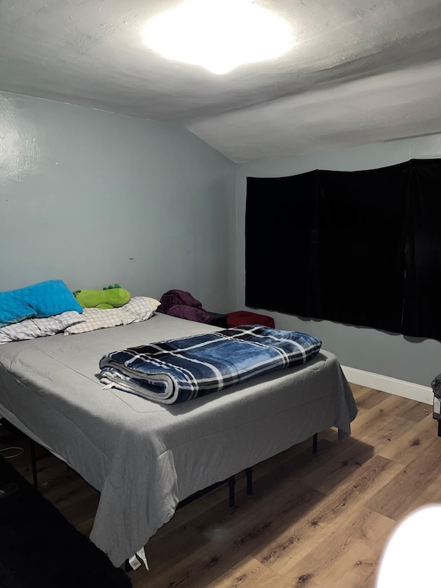 bedroom featuring lofted ceiling and wood finished floors