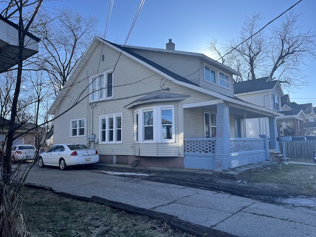 view of side of home with covered porch and a chimney