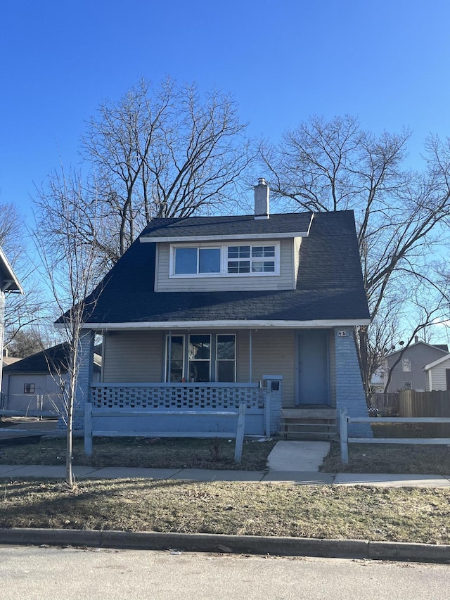 view of front of property featuring a porch, fence, and a chimney